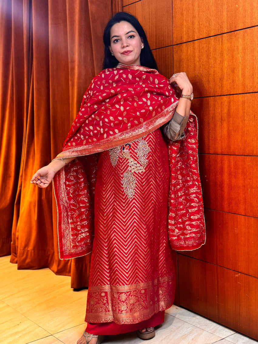Woman wearing a red traditional outfit with a matching shawl against a wooden panel background