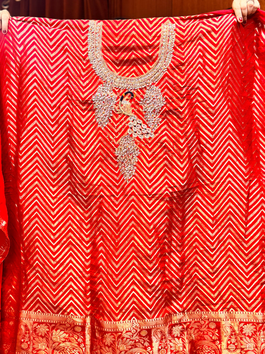 Red garment with intricate white embroidery held up against a dark background