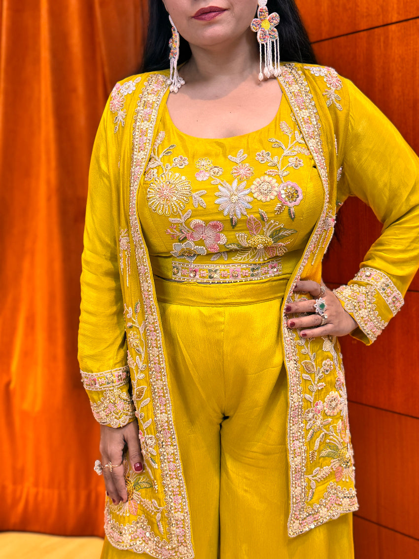Woman wearing a yellow embroidered outfit with a matching jacket against an orange background