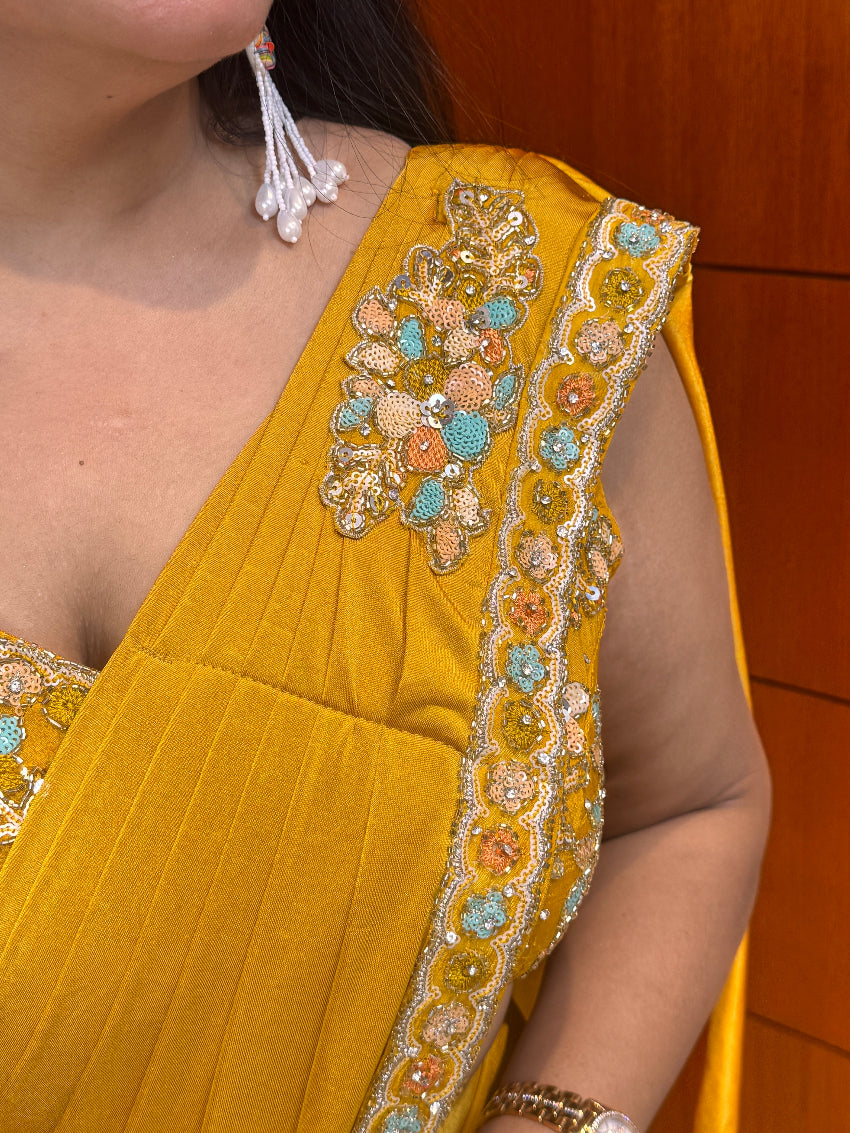 Close-up of a yellow garment with intricate beadwork on a wooden surface.