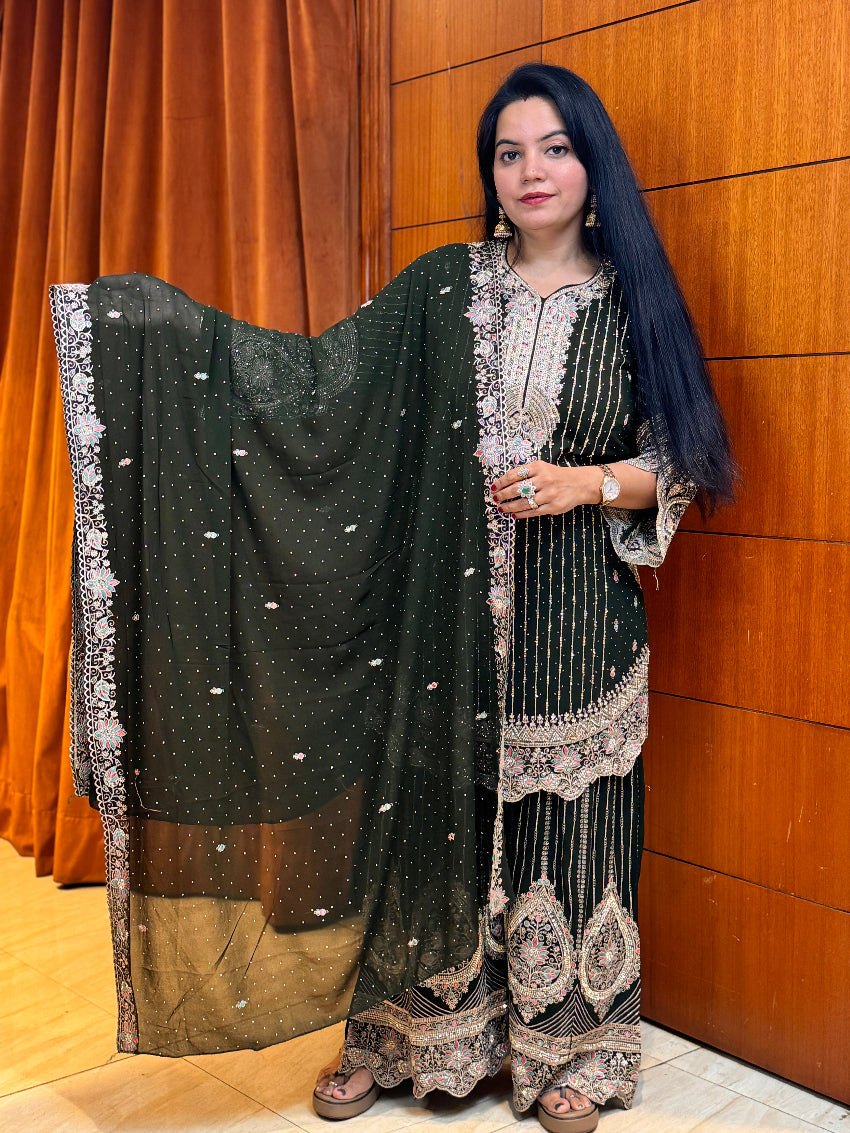 Woman in traditional attire standing against a wooden paneled wall.