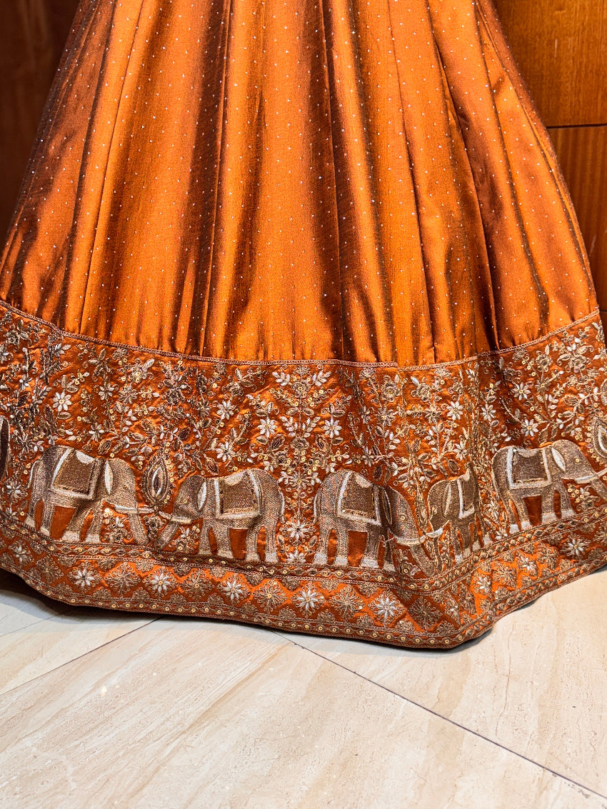 Orange embroidered fabric with elephant patterns on a wooden surface