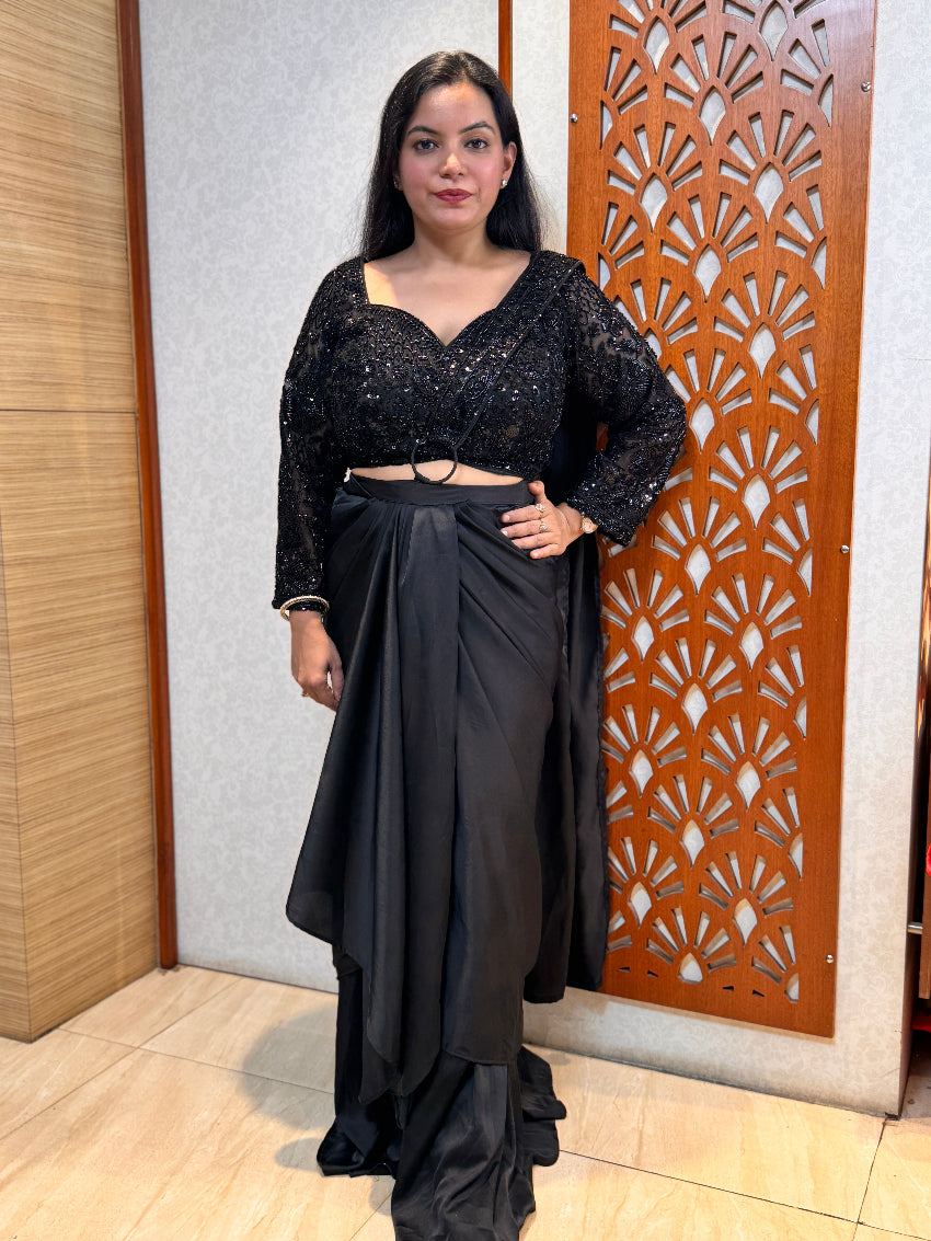 Woman in a black outfit standing in front of a decorative wooden panel.