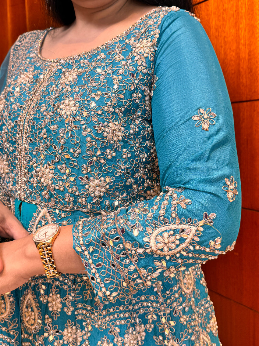 Close-up of a blue embroidered garment with intricate patterns and embellishments.