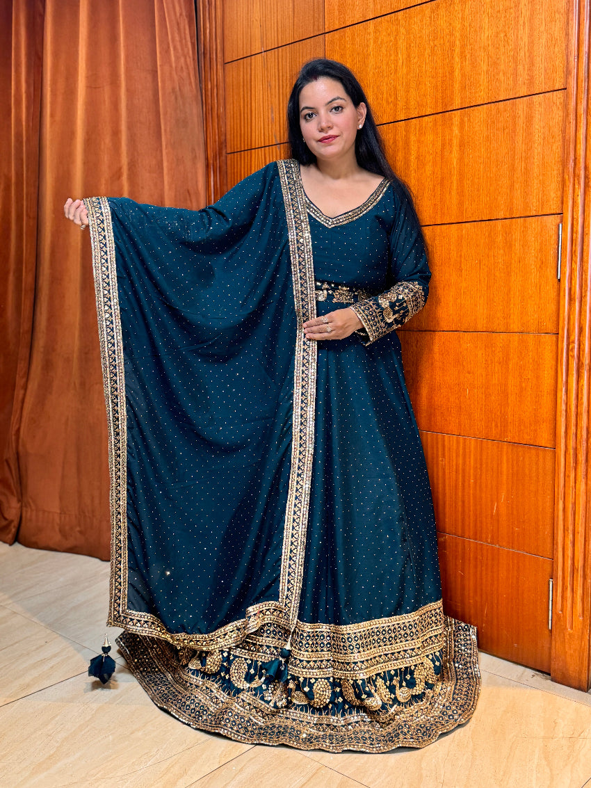 Woman wearing a blue traditional outfit with intricate designs against a wooden panel background