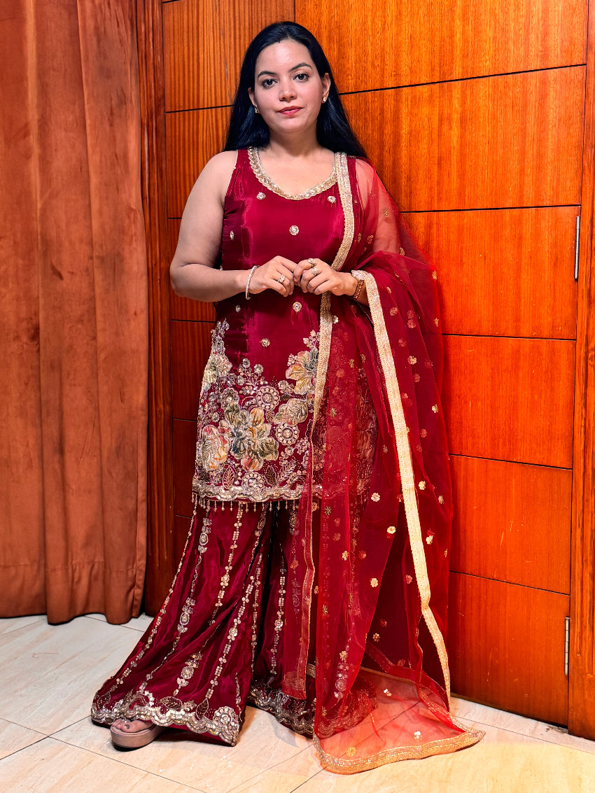 Woman in a red traditional outfit standing against a wooden panel background