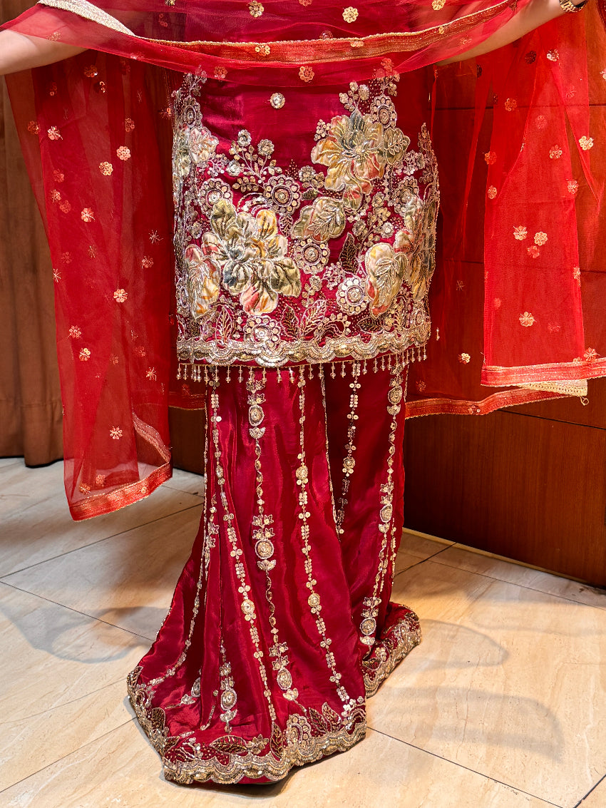 Red embroidered saree with gold details on a wooden surface