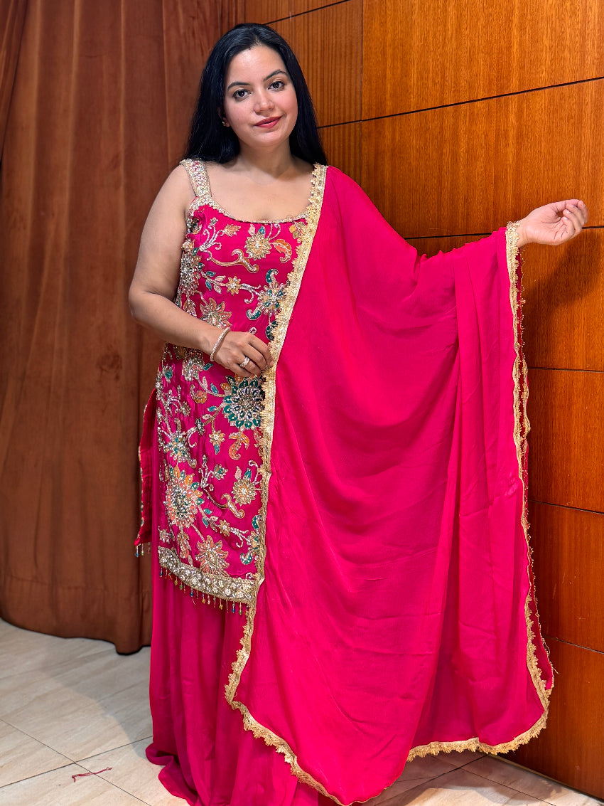 Woman in a pink traditional outfit with a matching dupatta against a wooden background
