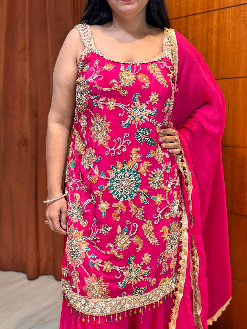 Woman wearing a pink embroidered traditional outfit against a wooden background