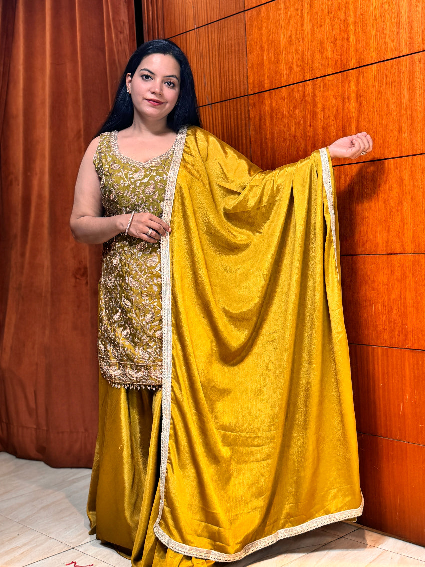 Woman wearing a traditional yellow saree with a gold blouse against a wooden panel background