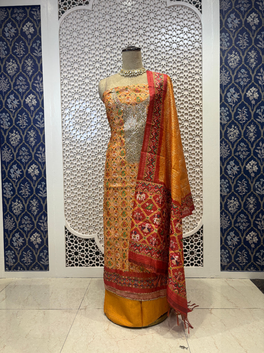 Mannequin wearing a traditional outfit with a floral pattern against a decorative wall.