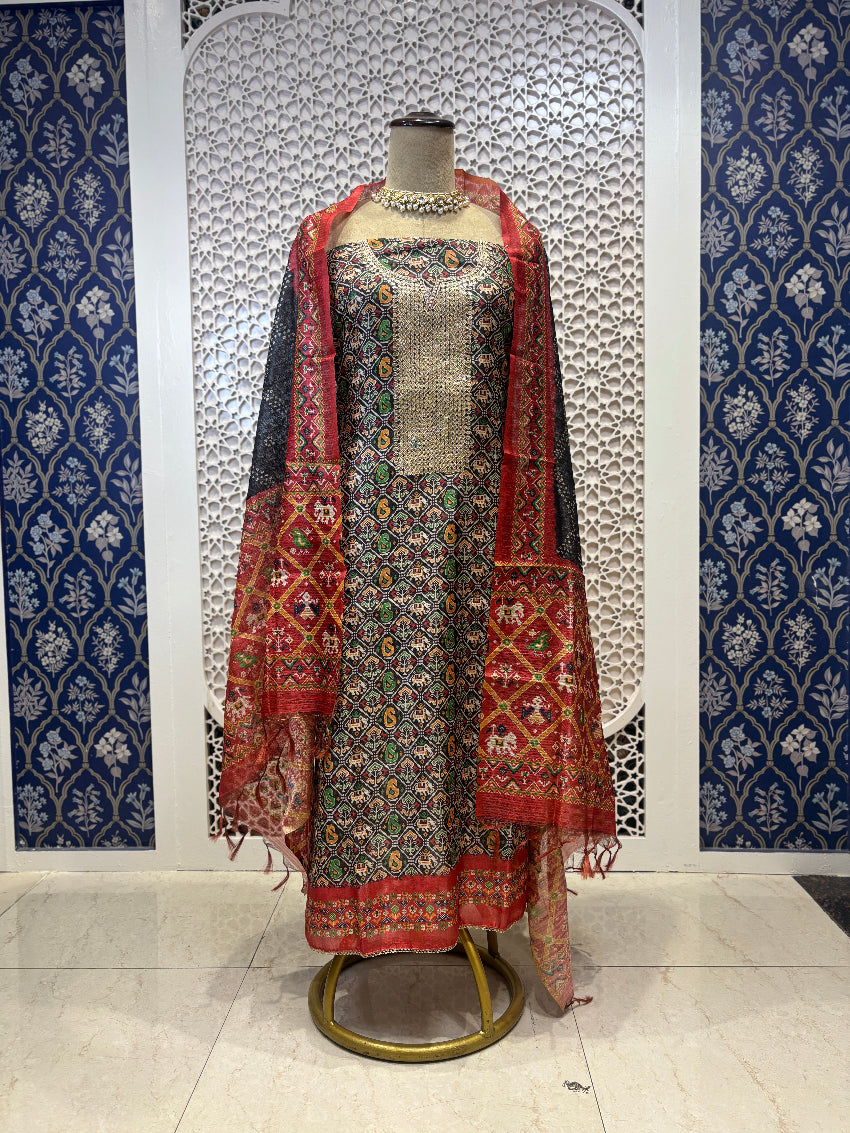Traditional outfit with a patterned shawl on a mannequin against a decorative wall.