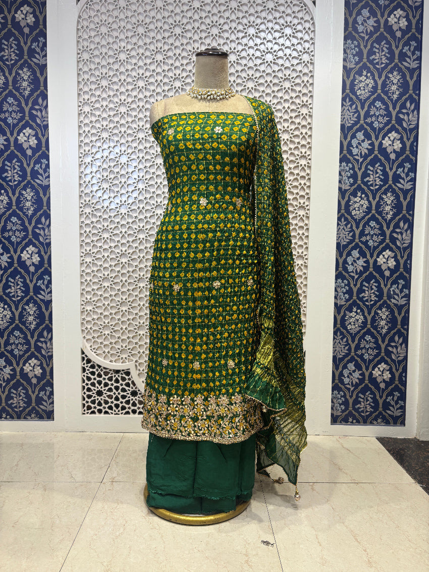 Green embroidered traditional outfit on a mannequin against a decorative wall.
