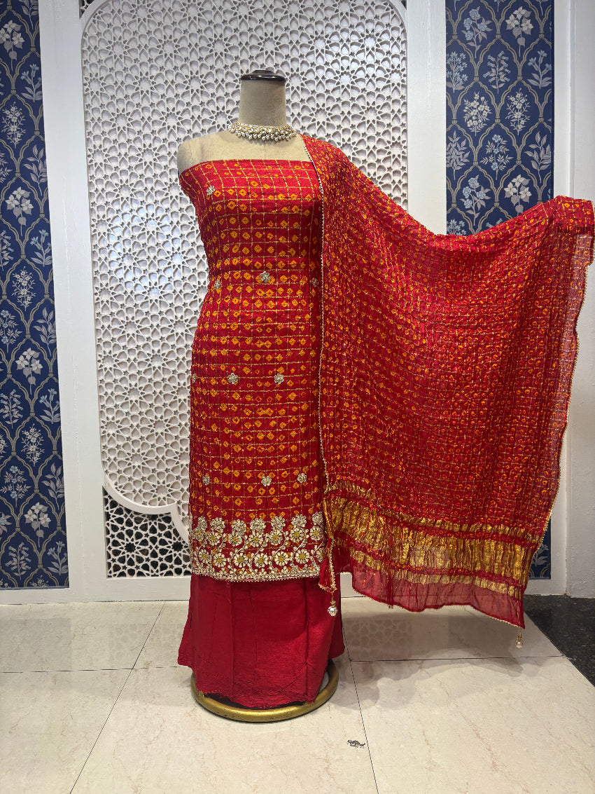 Red and gold traditional outfit on a mannequin against a decorative wall.