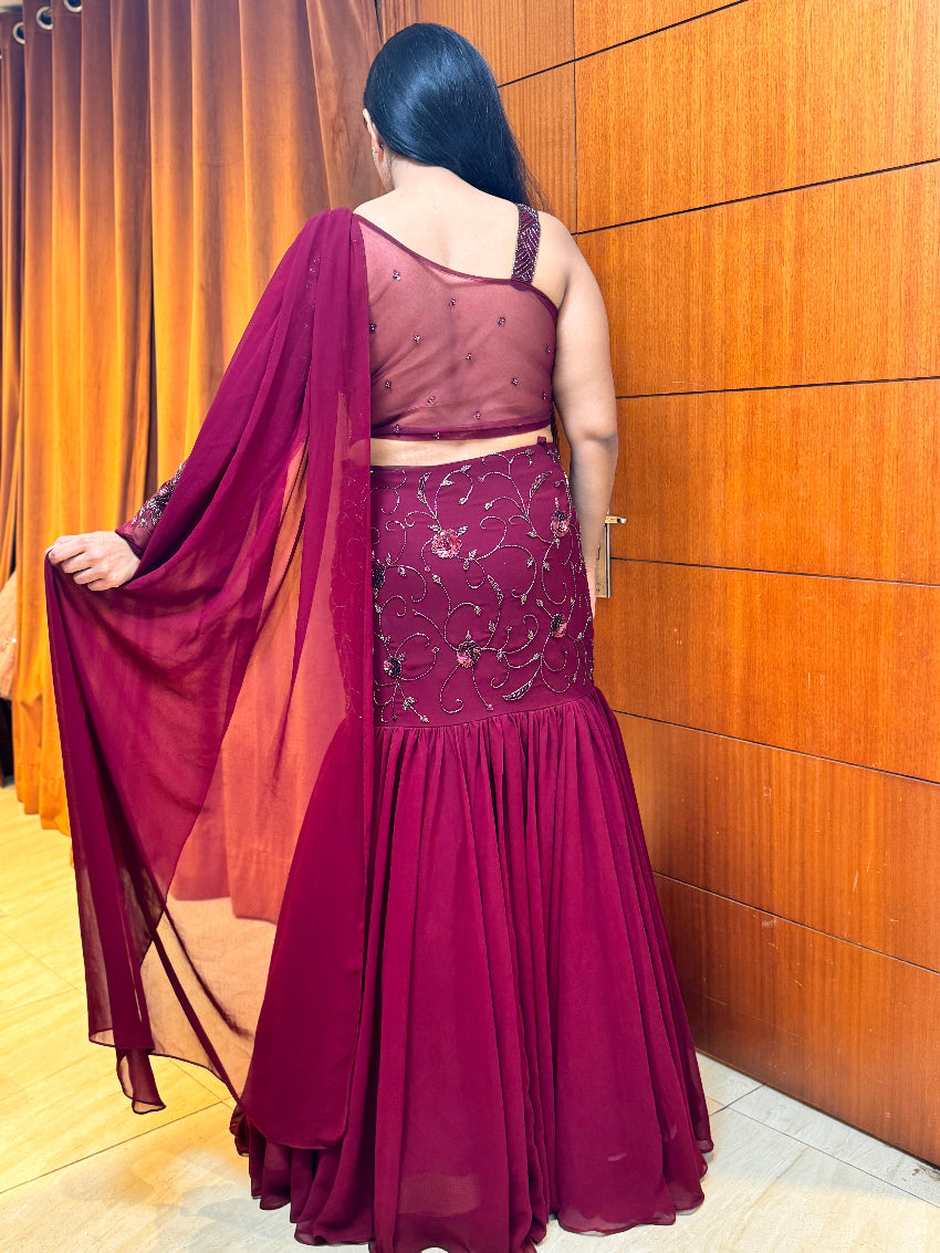 Woman wearing a maroon saree with a wooden panel background