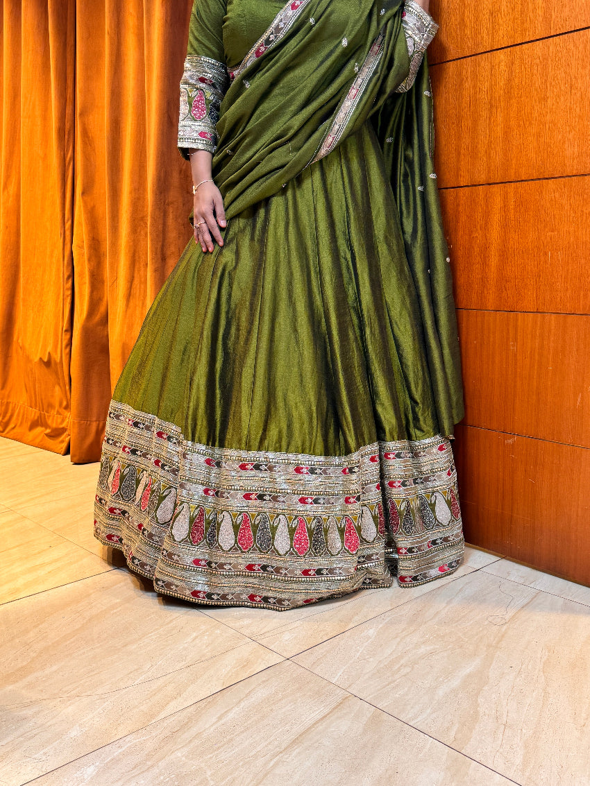 Green saree with intricate patterns draped over a wooden surface.