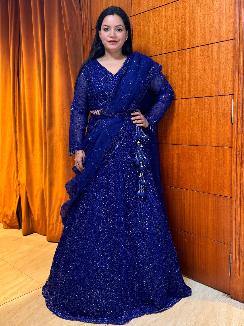 Woman in a blue saree standing against a wooden panel background