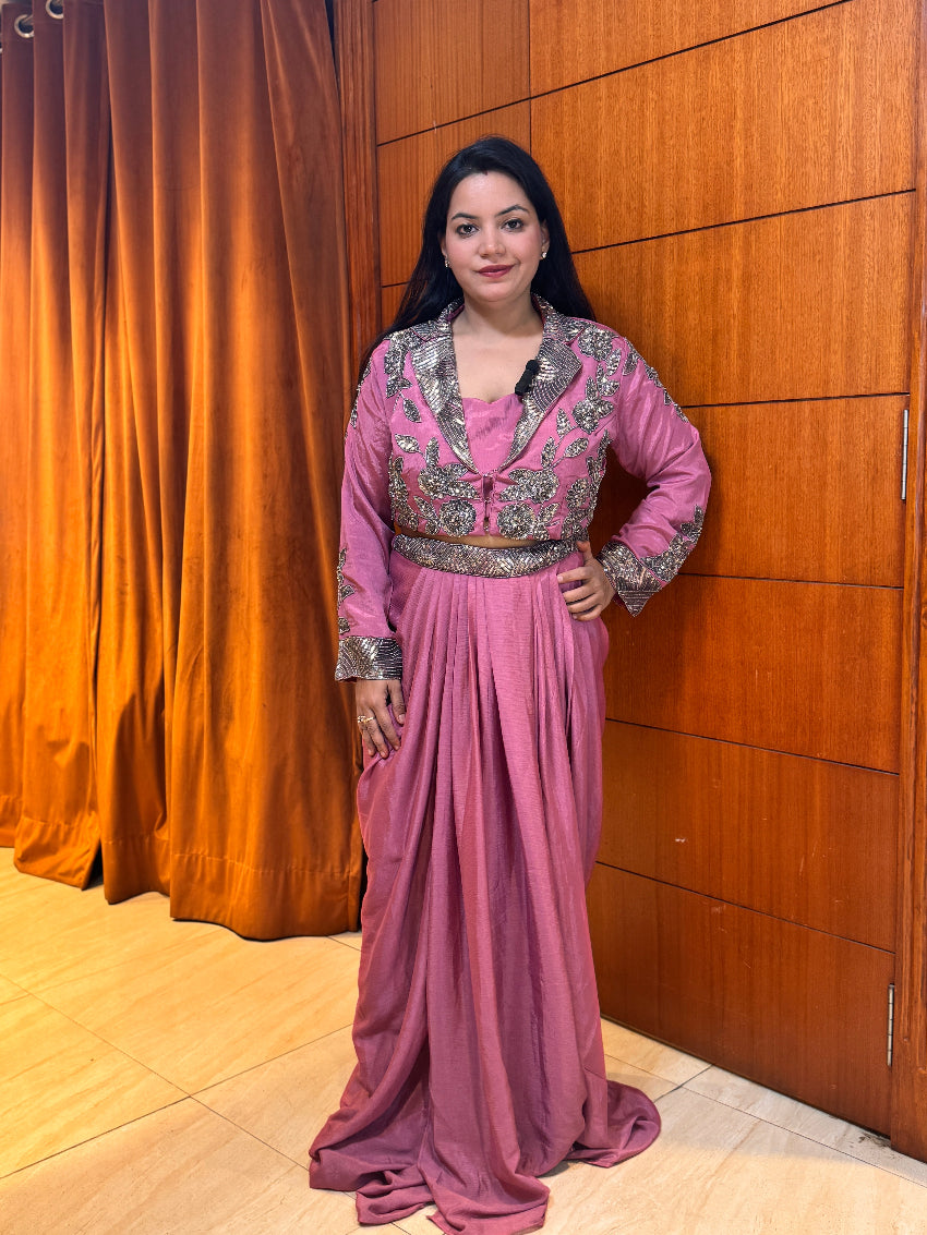 Woman in a pink traditional outfit standing against a wooden panel background