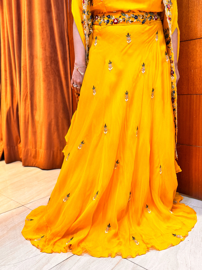 Yellow embroidered saree with a matching blouse against an orange curtain background