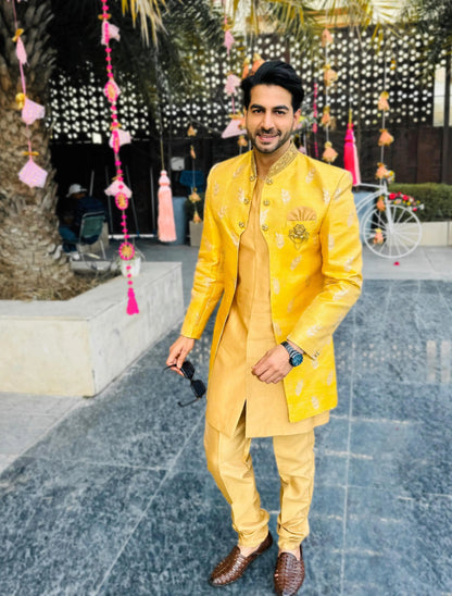 Dazzle in our Mango Yellow Front Open Asymmetrical Achkan with Golden Kurta Pant, the epitome of modern elegance for sangeet, haldi, cocktail, reception, and wedding festivities. Radiating vibrancy with its mango yellow hue, this ensemble boasts intricate asymmetrical design for a contemporary edge. Paired with golden kurta pants, it exudes regal charm and sophistication. Step into the limelight with confidence, making a bold statement on your special day.