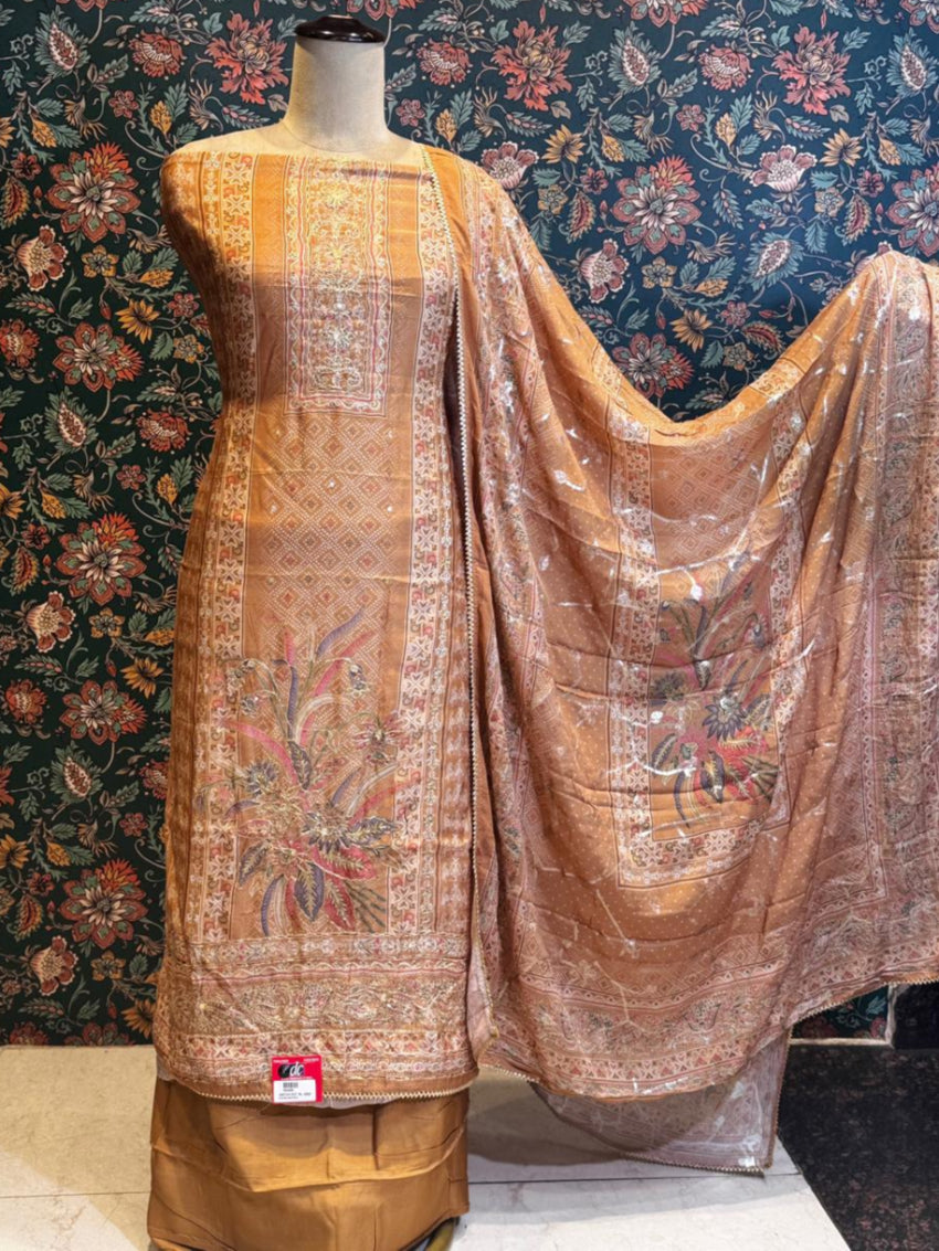 Traditional embroidered saree on a mannequin against a floral wallpapered wall.