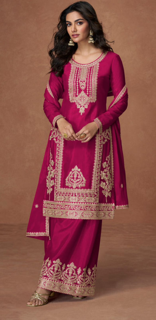 Woman wearing a pink traditional outfit with intricate gold embroidery on a brown background