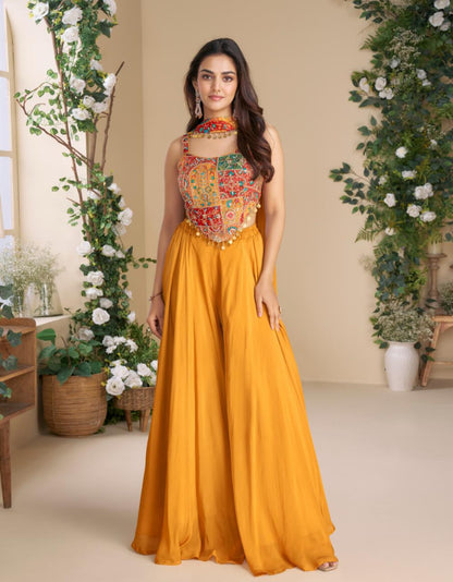 Woman in a colorful top and yellow skirt standing in a decorated room with plants.