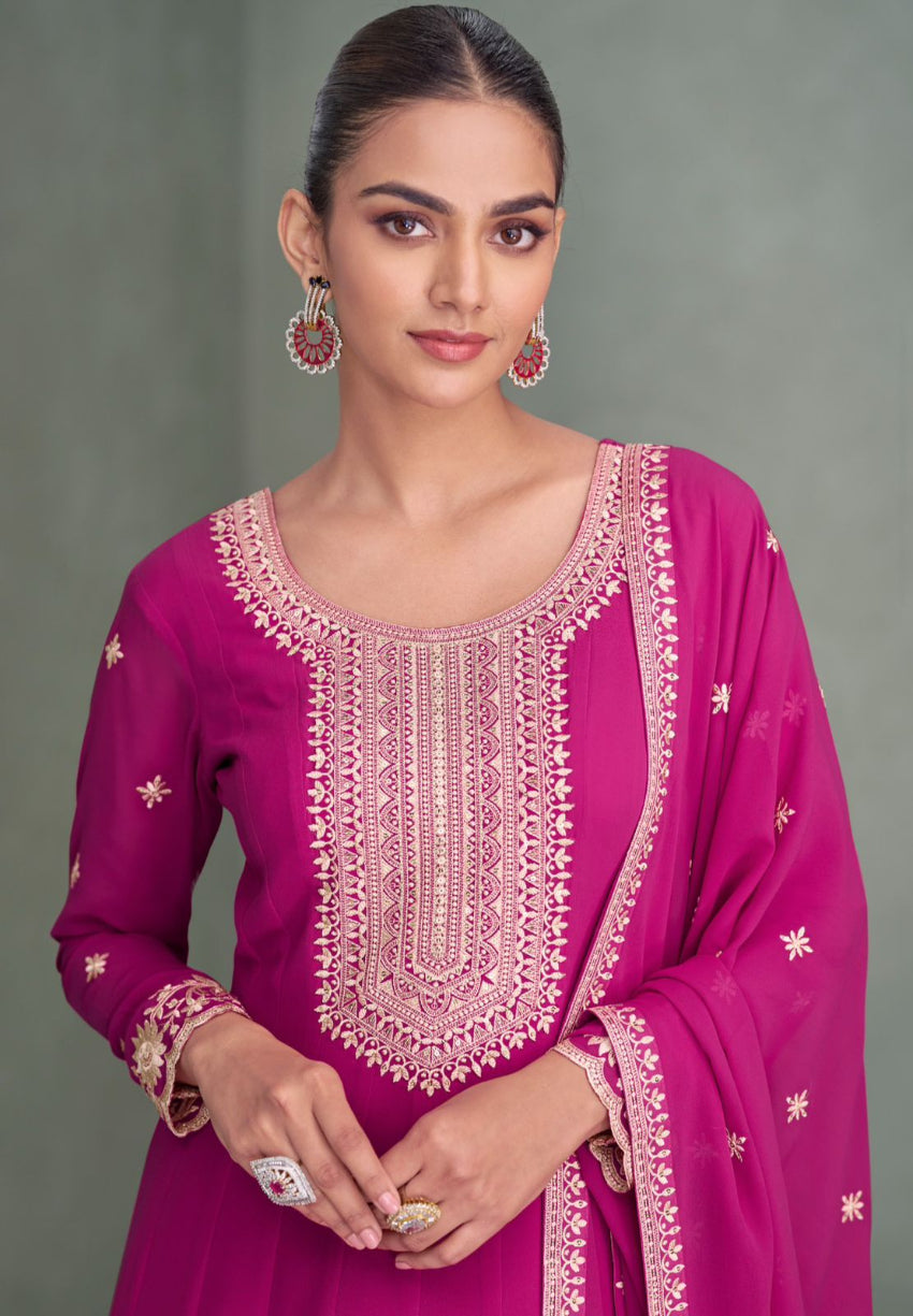 Woman wearing a pink embroidered traditional outfit against a gray background