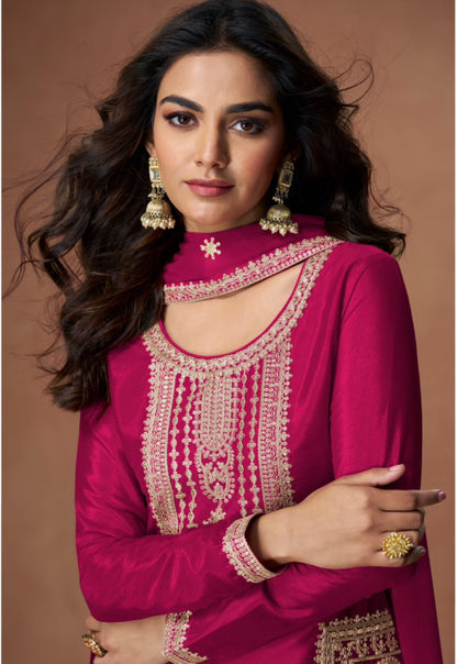 Woman wearing a pink traditional outfit with intricate designs on a brown background
