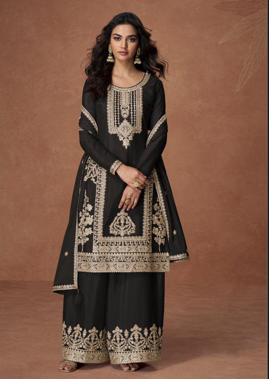 Woman wearing a black embroidered traditional outfit against a brown background
